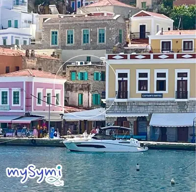 a boat is docked in the water next to buildings at My Symi Apartments in Symi
