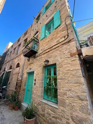 an old stone building with green doors and windows at My Symi Apartments in Symi