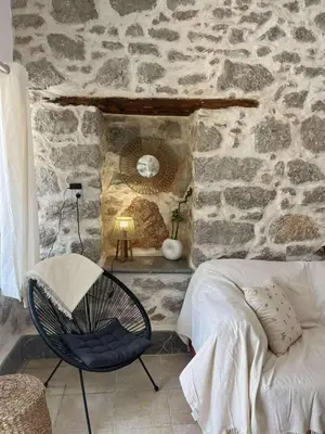 a bedroom with a stone wall with a rocking chair at Seaside House in Symi