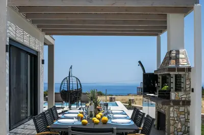 a dining table on a patio with a view of the ocean at Blue Sunrise Villa 1 in Afantou