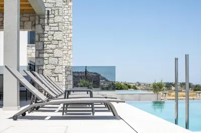 a row of lounge chairs next to a swimming pool at Blue Sunrise Villa 1 in Afantou