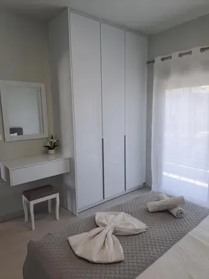 a white room with a bed with a dresser at Giannis Apartment in Afantou