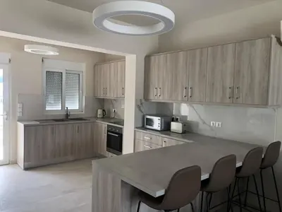 a kitchen with wooden cabinets and a table with chairs at Palm Marie - Rhodes in Kalithies