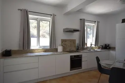 a kitchen with white cabinets and a sink and two windows at Sofia Villa Near Faliraki in Kalithies