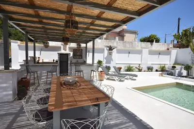 a patio with a table and chairs and a pool at Sofia Villa Near Faliraki in Kalithies