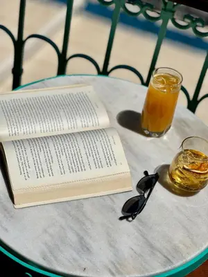 a book and glasses on a table with a drink at Lindiakos Villa AMI in Symi