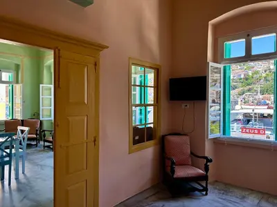 a room with a chair and a table and windows at Lindiakos Villa AMI in Symi