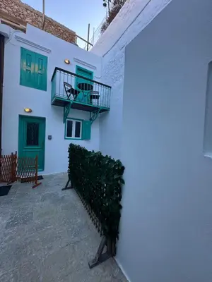 a white building with green doors and a balcony at Lindiakos Villa AMI in Symi