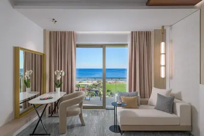 a living room with a couch and a table with a view of the ocean at Elysium Resort & Spa in Faliraki