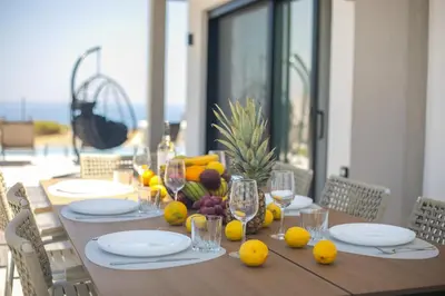 a dining table with fruits and wine glasses on it at Blue Sunrise Villa 2 in Afantou