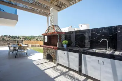 a kitchen with black countertops and a patio with a table at Blue Sunrise Villa 2 in Afantou