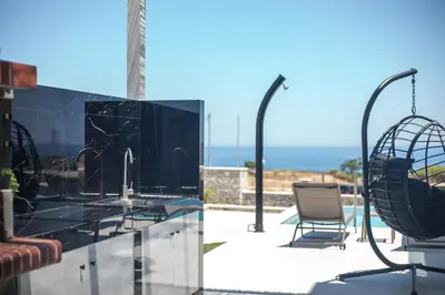 a patio with a glass table and a chair at Blue Sunrise Villa 2 in Afantou
