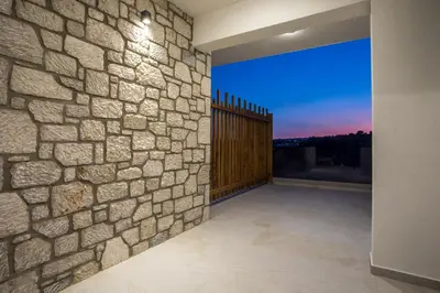 an empty room with a stone wall and a fence at Blue Sunrise Villa 2 in Afantou