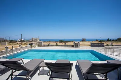 a swimming pool with chairs and a table and a swimming pool at Blue Sunrise Villa 2 in Afantou