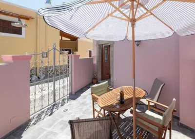 a table and chairs with an umbrella on a balcony at Casa Porolithos in Malona Village
