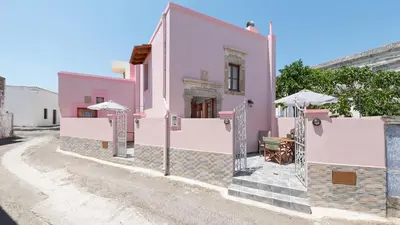 a pink house with stairs and umbrellas on a street at Casa Porolithos in Malona Village