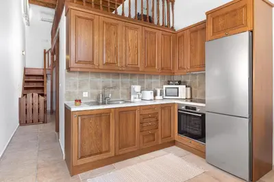a kitchen with wooden cabinets and a white refrigerator at Casa Porolithos in Malona Village