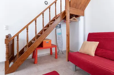a living room with a staircase and a red couch at Casa Porolithos in Malona Village