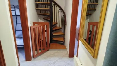 a hallway with a spiral staircase and a mirror at SteMaMaisonette in Afantou