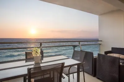 a balcony with a table with a view of the ocean at Coastal Mirage Sunset Reverie Luxury Seaview Apartment in Rhodes Town