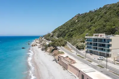 a beach next to a building and the ocean at Coastal Mirage Sunset Reverie Luxury Seaview Apartment in Rhodes Town