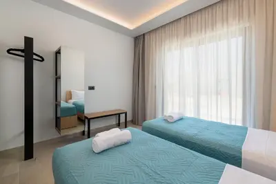 a hotel room with two beds and a window at Sunrays Pool Villas in Kalathos