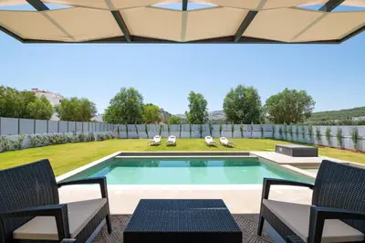 a swimming pool in a yard with chairs and a fence at Sunrays Pool Villas in Kalathos