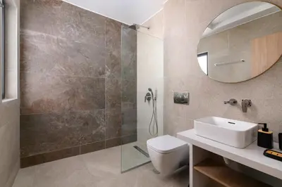 a bathroom with a shower and a sink and a mirror at Sunrays Pool Villas in Kalathos