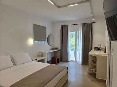 a bedroom with a bed and a desk and a window at Pension Zoi Luxury Room in Kolimbia