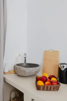 a sink and a basket of fruit on a counter at Pension Zoi Luxury Room in Kolimbia