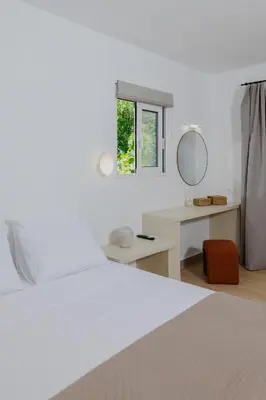 a bedroom with a white bed and a mirror at Pension Zoi Luxury Room in Kolimbia