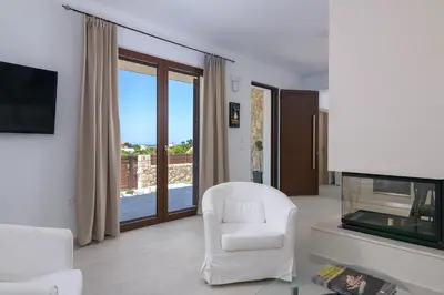 a living room with a white chair and a television at Ninalma Villa in Kalavárda