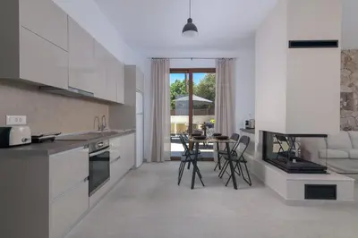 a kitchen with white cabinets and a table with chairs at Ninalma Villa in Kalavárda