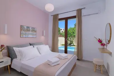a white bedroom with a bed and a sliding glass door at Ninalma Villa in Kalavárda