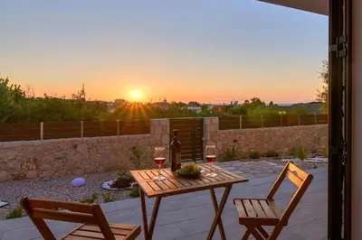 a table with two chairs and wine glasses on a patio at Ninalma Villa in Kalavárda