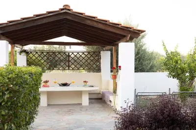 a pergola with a white table in a garden at Villa Angelina in Afantou