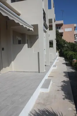 a white building with a sidewalk next to a building at Anemomilos View in Koskinou