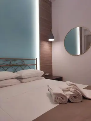 a bedroom with a white bed with a mirror at Anemomilos View in Koskinou