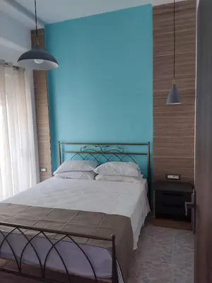 a bedroom with a large bed with a blue wall at Anemomilos View in Koskinou