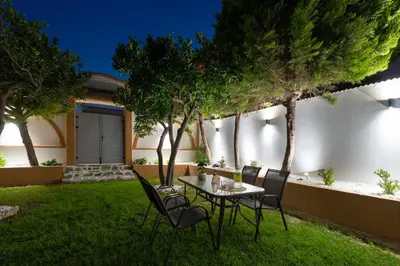 a table and chairs in the yard of a house at Duo Verde Celine Garden Apartment in Kremasti