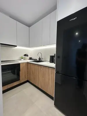 a kitchen with white cabinets and a black refrigerator at Aelios Petra sea view apartment 1 in Asgourou