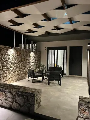 a living room with a table and a stone wall at Aelios Petra sea view apartment 1 in Asgourou