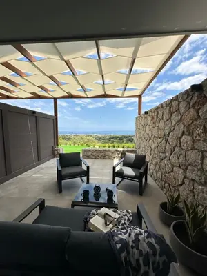 a living room with a couch and chairs and a stone wall at Aelios Petra sea view apartment 1 in Asgourou