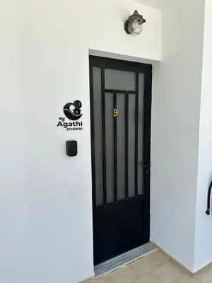 a black door on the side of a white building at My Agathi Studios in Haraki