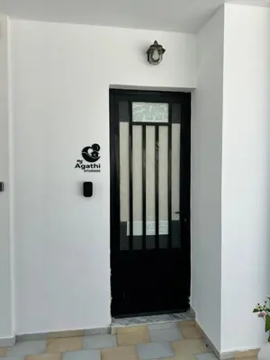 a black door on the side of a white building at My Agathi Studios in Haraki
