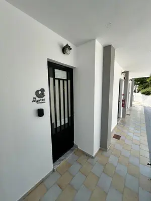 a black door on the side of a white building at My Agathi Studios in Haraki