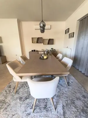 a dining room with a wooden table and white chairs at Villa Agapi in Pastida