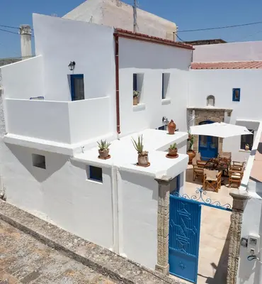 a white house with a blue door and a patio at Villa Gennadi Essence in Gennadi