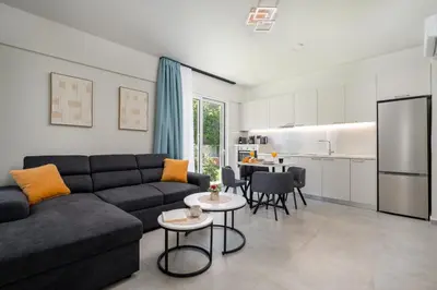 a living room with a couch and a kitchen at Duo Verde Soil Garden Apartment in Kremasti