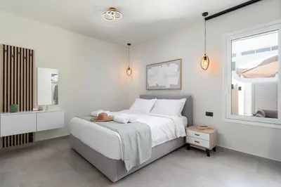 a white bedroom with a bed and a window at Duo Verde Soil Garden Apartment in Kremasti